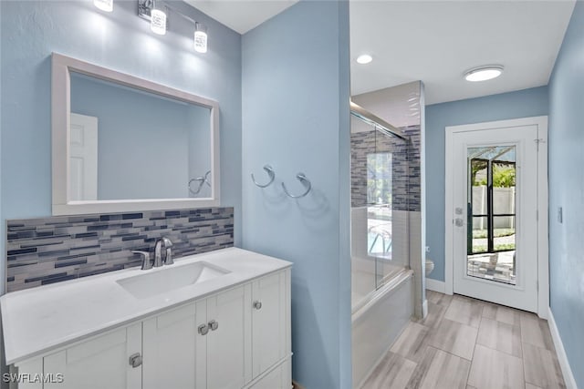 full bathroom with vanity, backsplash, toilet, and combined bath / shower with glass door