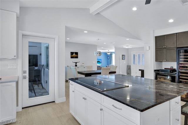 kitchen featuring a center island, lofted ceiling with beams, black electric cooktop, pendant lighting, and white cabinets