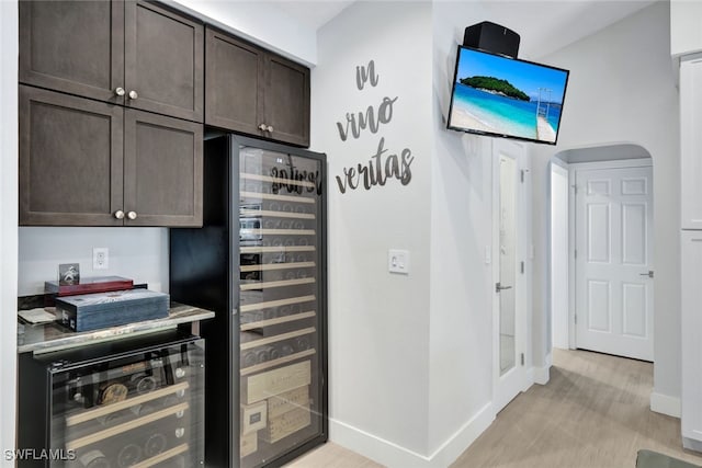 interior space featuring dark brown cabinets, beverage cooler, and light wood-type flooring