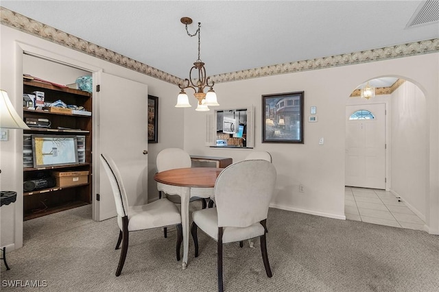 dining space with light carpet and a chandelier