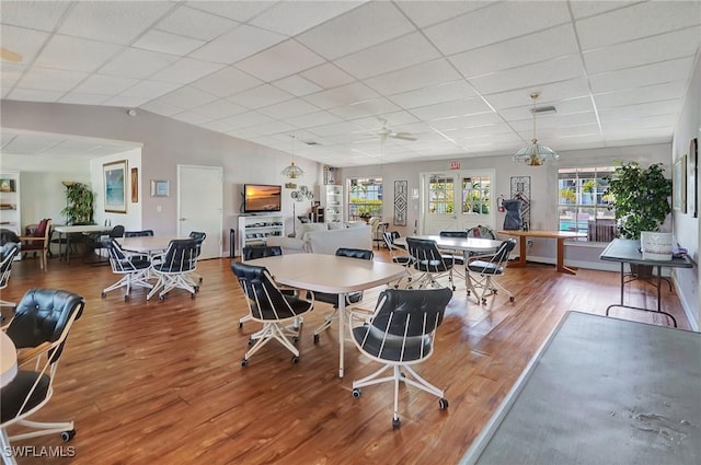 dining space with a drop ceiling, hardwood / wood-style flooring, and lofted ceiling