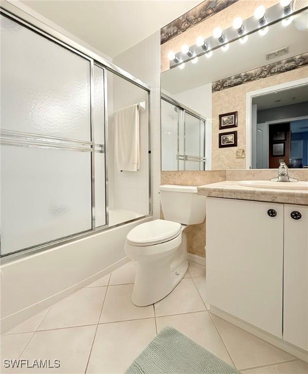 full bathroom featuring toilet, bath / shower combo with glass door, tile patterned flooring, and vanity