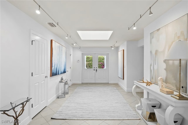 entrance foyer with french doors, track lighting, a skylight, and light tile patterned floors