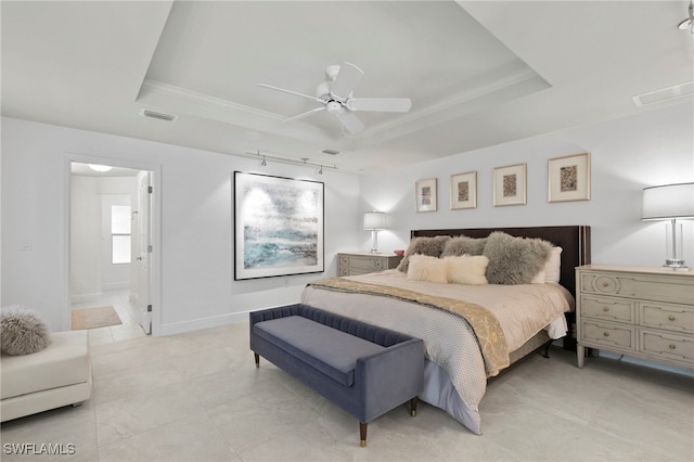 bedroom featuring ceiling fan, a tray ceiling, and ensuite bath