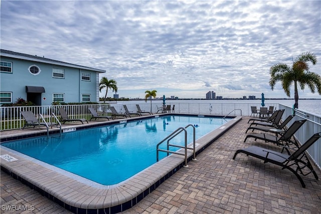 view of swimming pool with a water view and a patio