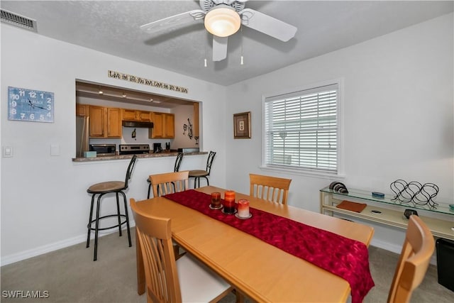 dining room featuring light carpet, ceiling fan, and a textured ceiling