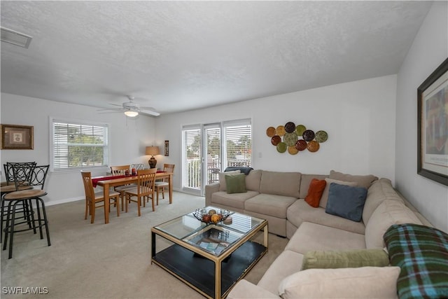 carpeted living room featuring ceiling fan and a textured ceiling