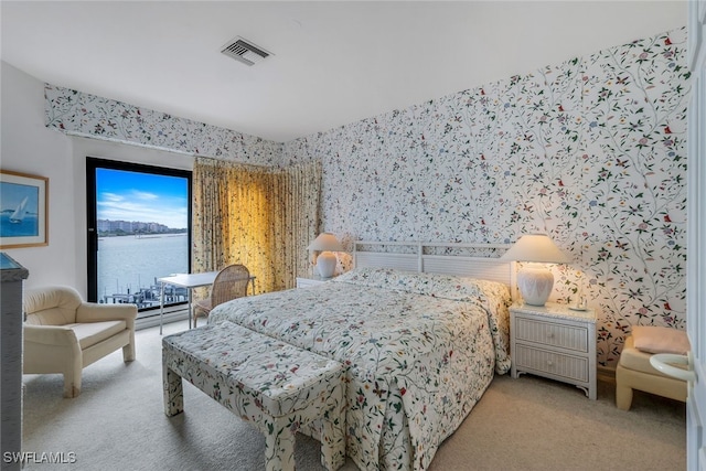 bedroom featuring a water view and light carpet