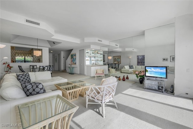 carpeted living room featuring a notable chandelier