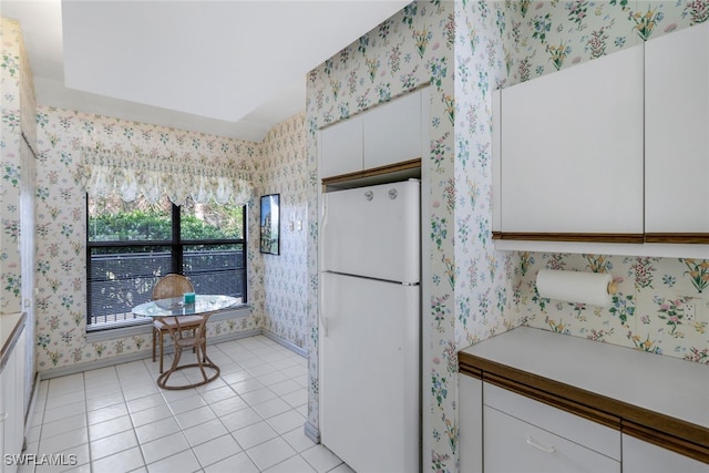 kitchen featuring white cabinets, white fridge, and light tile patterned flooring