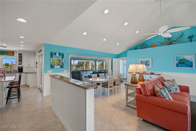 living room with ceiling fan, lofted ceiling, and light tile patterned flooring