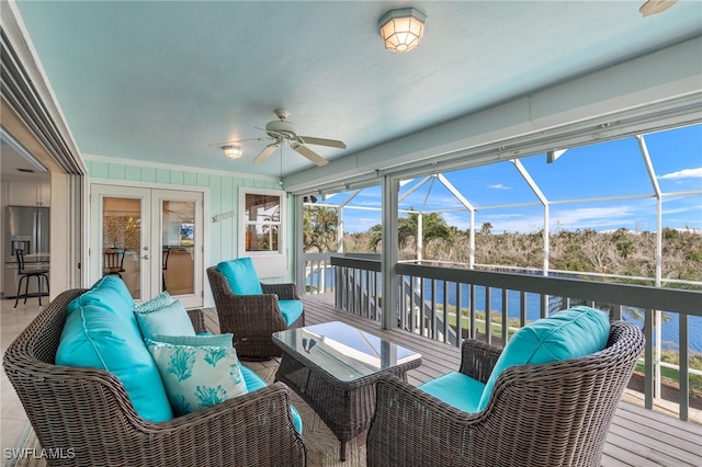 sunroom / solarium with ceiling fan, a water view, and french doors