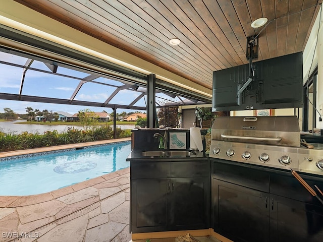 view of pool with a patio, area for grilling, sink, a water view, and glass enclosure