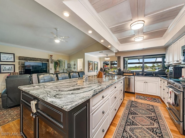 kitchen with light stone counters, white cabinetry, a center island, and stainless steel appliances