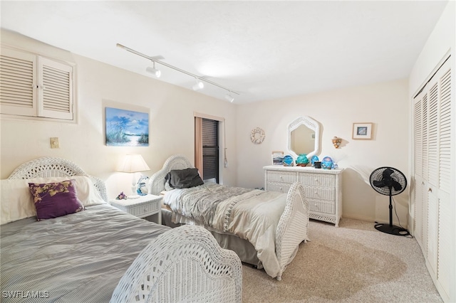 carpeted bedroom with rail lighting and a closet