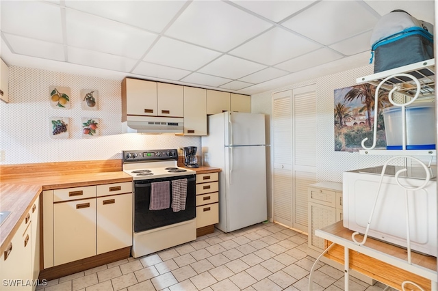 kitchen featuring cream cabinets, white appliances, butcher block countertops, and a drop ceiling