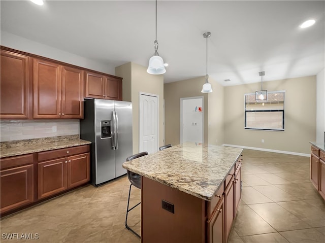 kitchen featuring a kitchen island, pendant lighting, backsplash, and stainless steel fridge