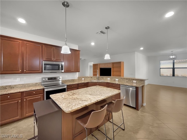 kitchen featuring decorative light fixtures, kitchen peninsula, appliances with stainless steel finishes, and a breakfast bar area