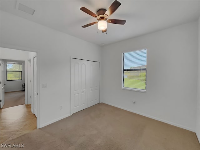 unfurnished bedroom featuring ceiling fan, a closet, and light carpet