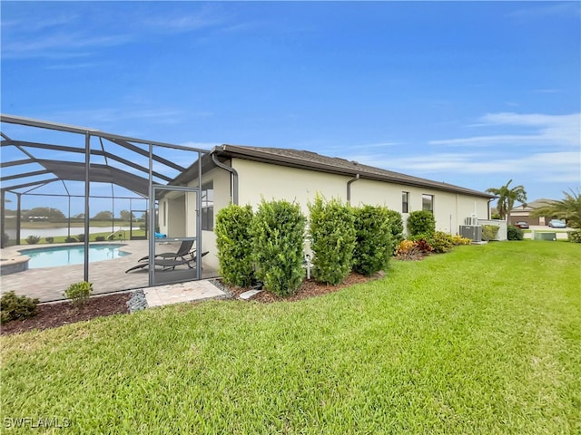 back of house with glass enclosure, central AC, a patio area, and a yard