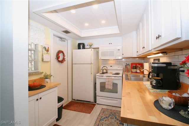 kitchen with white cabinetry, white appliances, a tray ceiling, and sink