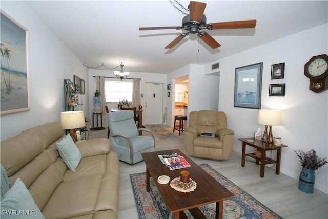 living room featuring ceiling fan with notable chandelier and light hardwood / wood-style floors