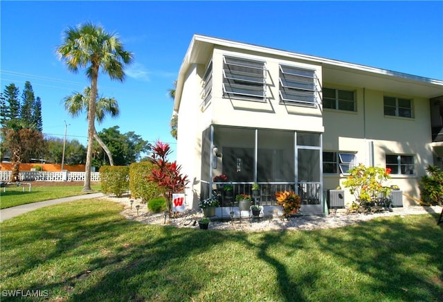 rear view of property with a sunroom, a yard, and central air condition unit