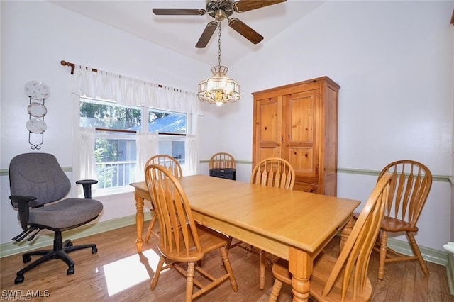 dining space with vaulted ceiling, ceiling fan with notable chandelier, and light hardwood / wood-style flooring