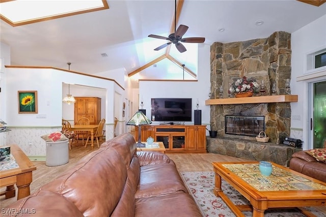 living room featuring lofted ceiling, light wood-type flooring, a fireplace, and ceiling fan