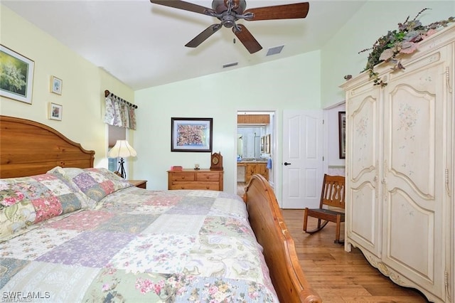 bedroom with ceiling fan, ensuite bathroom, light hardwood / wood-style flooring, and vaulted ceiling