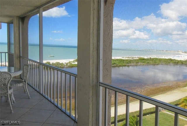 unfurnished sunroom featuring a water view and a view of the beach