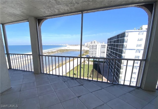 unfurnished sunroom featuring a beach view and a water view