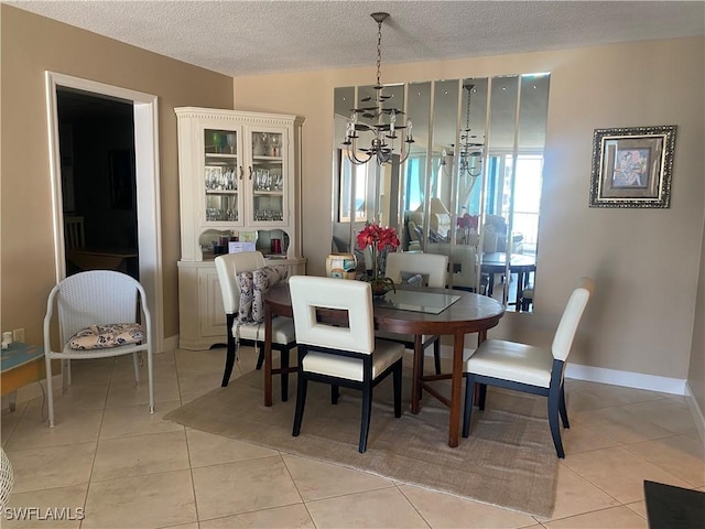 dining space featuring light tile patterned floors, a textured ceiling, and an inviting chandelier