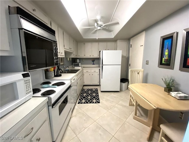 kitchen with sink, light tile patterned floors, ceiling fan, a tray ceiling, and white appliances