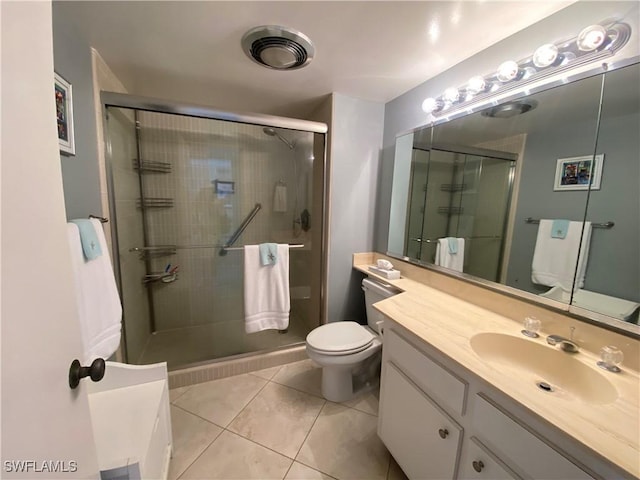 bathroom with a shower with door, vanity, tile patterned floors, and toilet