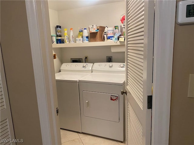 clothes washing area featuring light tile patterned floors and independent washer and dryer