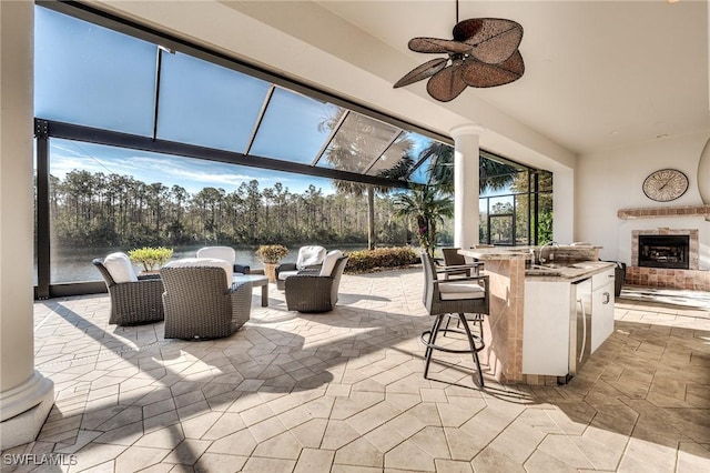 view of patio / terrace with an outdoor living space with a fireplace, a wet bar, and ceiling fan