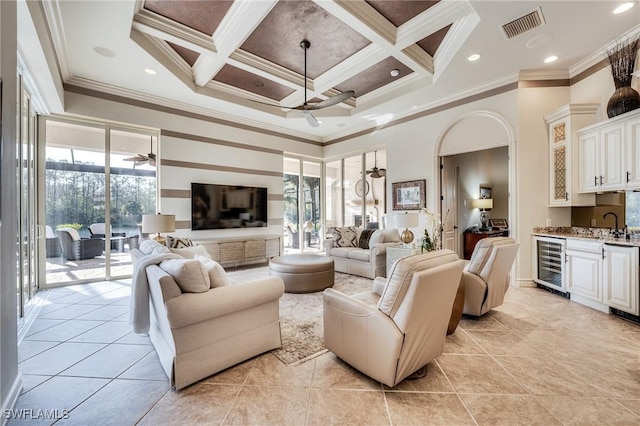 living room with coffered ceiling, ceiling fan, indoor bar, and beverage cooler