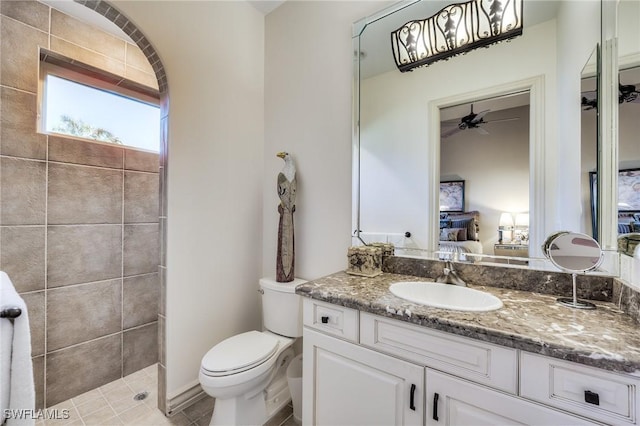 bathroom with vanity, a tile shower, and toilet