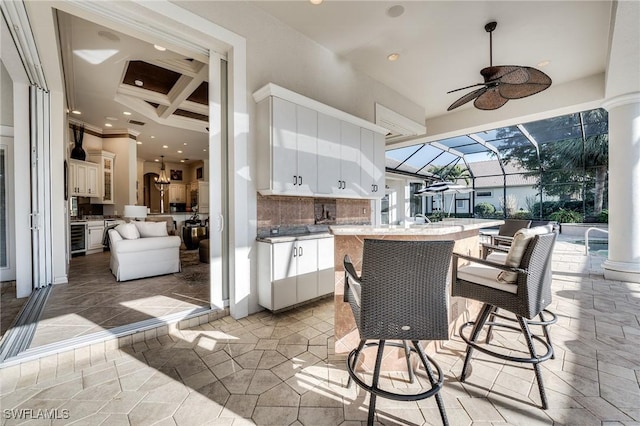 view of patio featuring a bar, area for grilling, wine cooler, a lanai, and ceiling fan