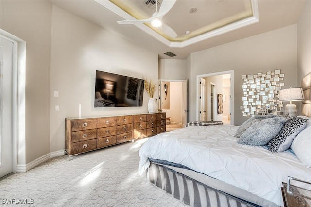 bedroom with a tray ceiling, ensuite bathroom, ceiling fan, and a towering ceiling