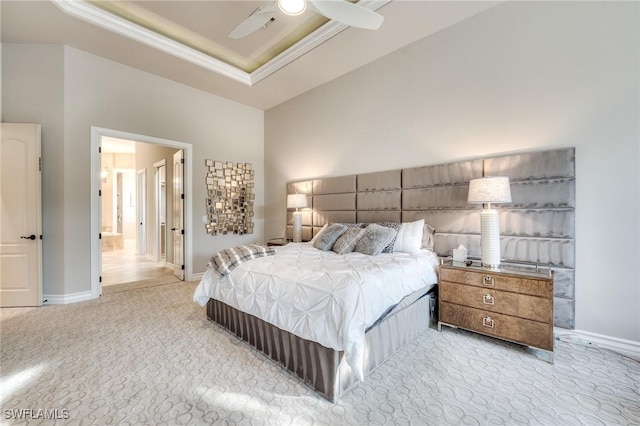 bedroom featuring ornamental molding, light carpet, ensuite bath, and a tray ceiling