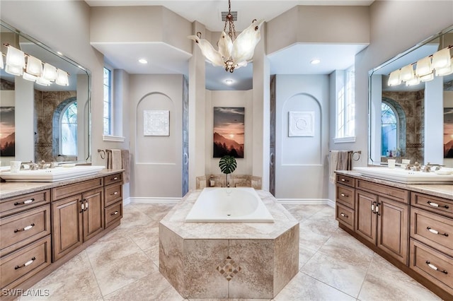 bathroom featuring vanity, a relaxing tiled tub, and a chandelier