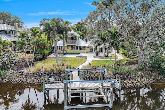 view of dock featuring a water view, a yard, and a patio area