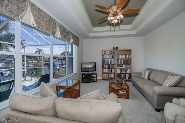 carpeted living room featuring a tray ceiling and ceiling fan