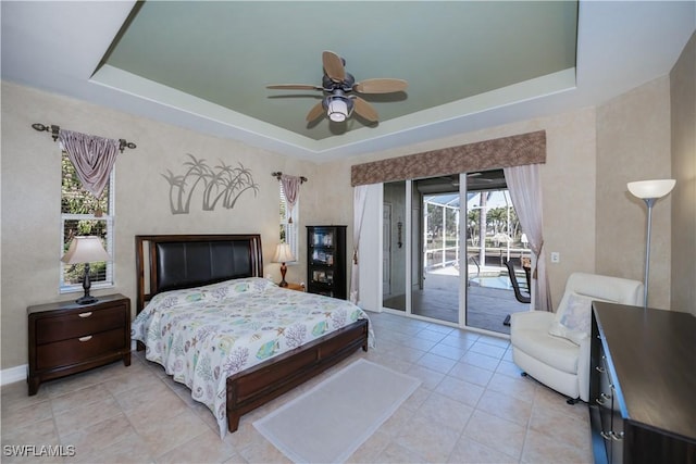 tiled bedroom with access to outside, ceiling fan, and a tray ceiling