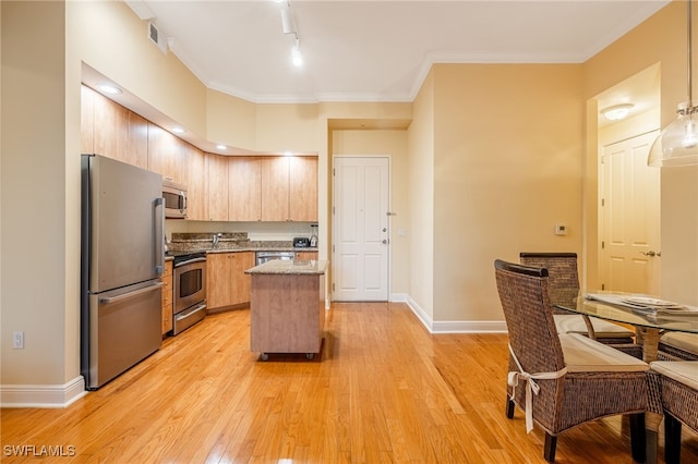 kitchen featuring light hardwood / wood-style flooring, appliances with stainless steel finishes, light brown cabinets, a kitchen island, and light stone counters