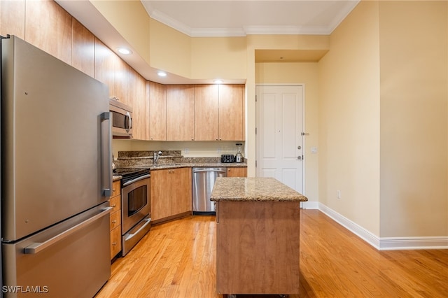 kitchen featuring light stone countertops, appliances with stainless steel finishes, a kitchen island, light hardwood / wood-style floors, and ornamental molding