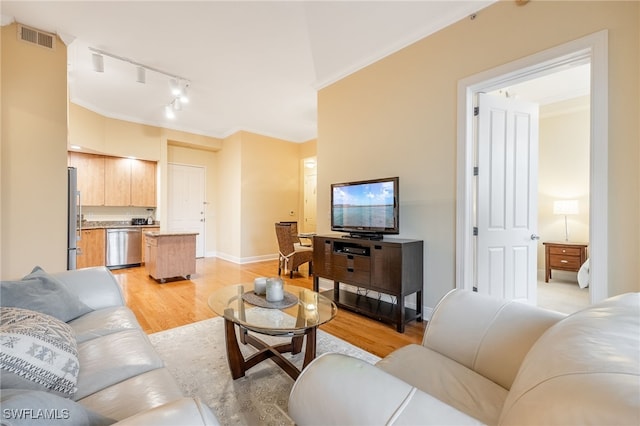 living room featuring track lighting, ornamental molding, and light hardwood / wood-style floors