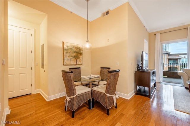 dining room with electric panel, ornamental molding, and light hardwood / wood-style floors